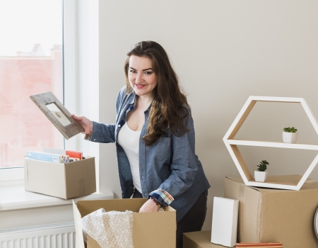 smiling portrait young woman unpacking cardboard boxes